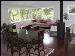 This open family space is part of a two story addition to a mid-century home in Wallingford. The room contains a living and dining space with an area for an artist's studio. Large windows give the space the feeling of a wide open tree house. The vaulted ceiling with skylights and cove lighting enhance the open feel. Stainless steel cable rail and the simple lines of the wood stove add to the contemporary style.