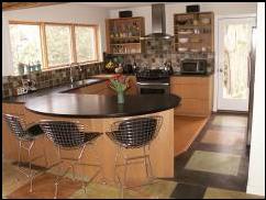 This contemporay kitchen is part of an addition and renovation to a mid-centuty home in Wallingford. Some of the sustainable elements in this kitchen include a Richlite contertop on the peninsula, and 100% recyclable plate steel on the other counters. The floor is radiantly heated stained concrete and cork. The cabinets are rift sawn white oak veneer. Windows are placed with overhangs to maximize solar heat gain in the winter and minimize it in the summer.